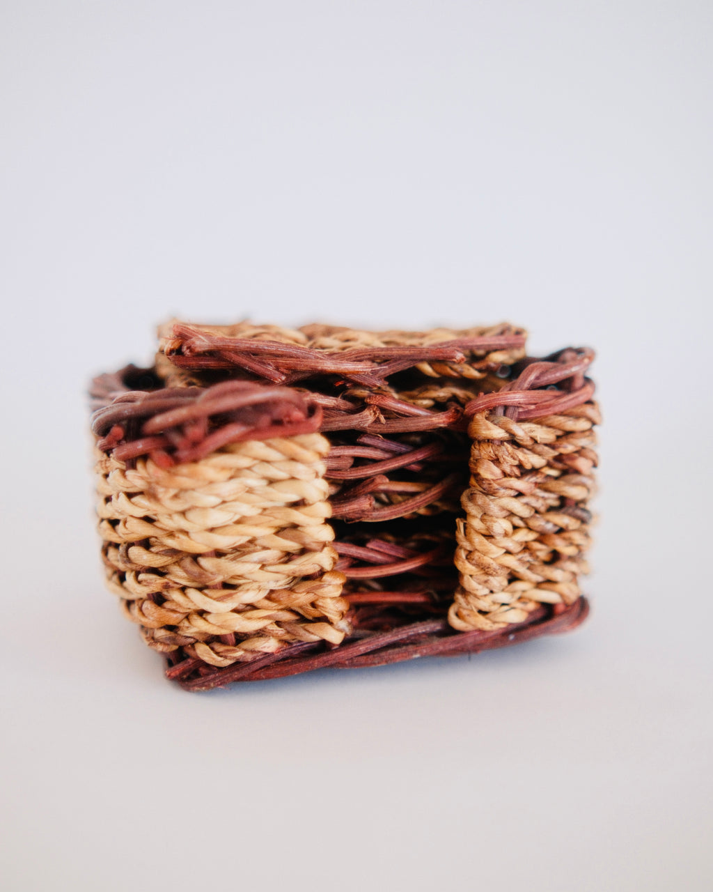 Set of six vintage hand woven wicker drink coasters displayed around matching square holder - Eulogy Vintage