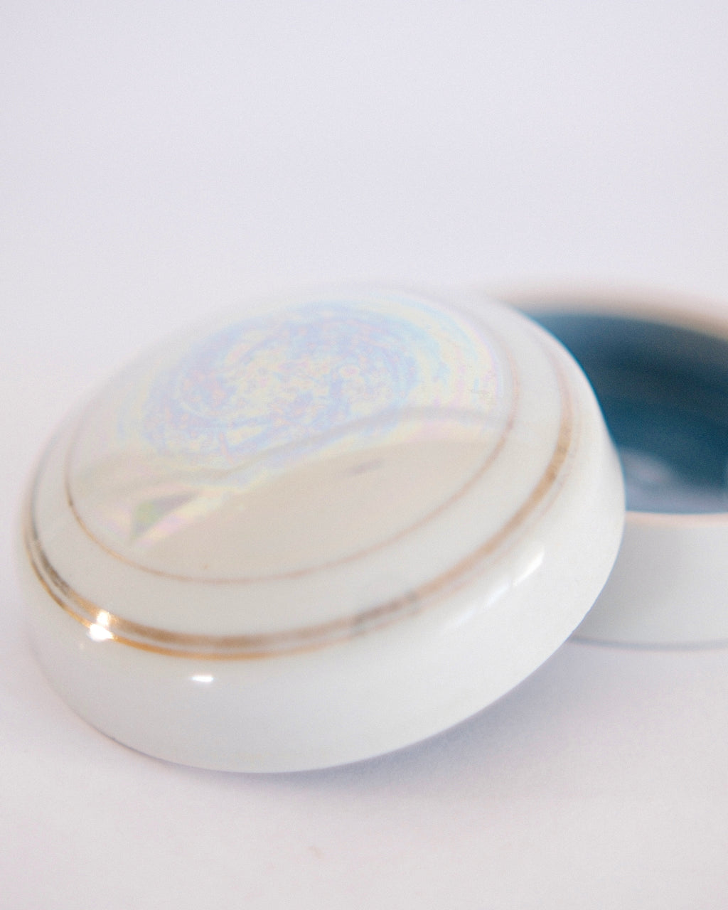 Round vintage iridescent white porcelain trinket box with lid off showing deep blue interior - Eulogy Vintage
